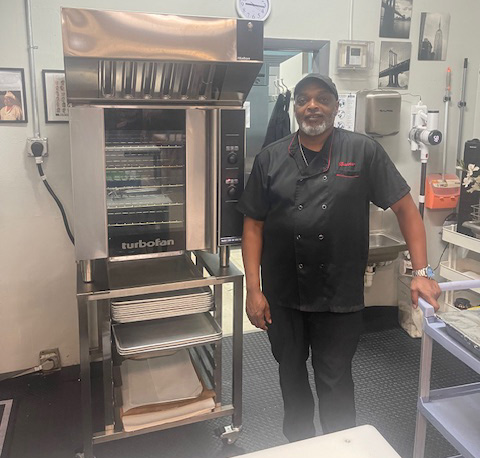 Chef Bridges Baxter stands beside the new state-of-the-art convection oven in the Heartbeat Denver kitchen.